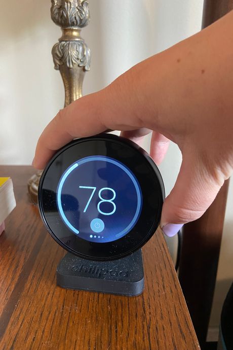 A hand rotating a dial on a round remote control.