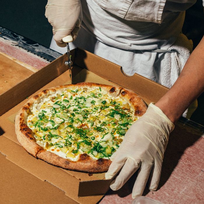 Four small pizzas in open brown pizza boxes