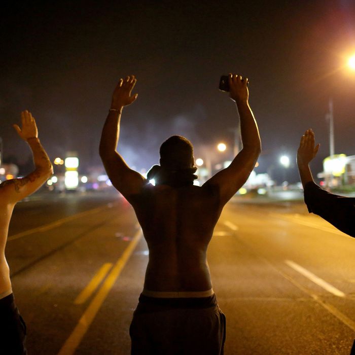 Demonstrators raise their arms and chant, “Hands up, Don’t Shoot”, as police clear them from the street as they protest the shooting death of Michael Brown on August 17, 2014 in Ferguson, Missouri.