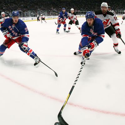 Dan Girardi #5 of the New York Rangers controls the puck against Travis Zajac #19 of the New Jersey Devils