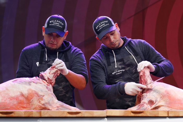 Two butchers standing next to each other, each carving his own pig.