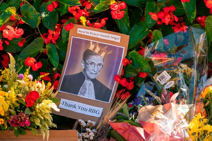 A photograph of Ruth Bader Ginsburg surrounded by flowers at a memorial to her. New York Governor Cuomo has called for an RBG statue memorial in Brooklyn.