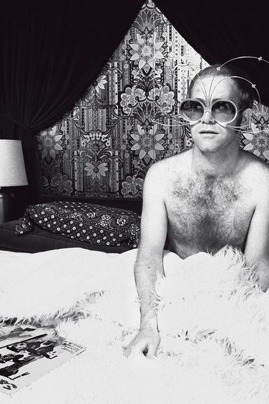 Elton John, having just woken up in his bed aboard his private plane.