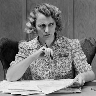 Serious worried woman at desk going over papers bills looking off to side.