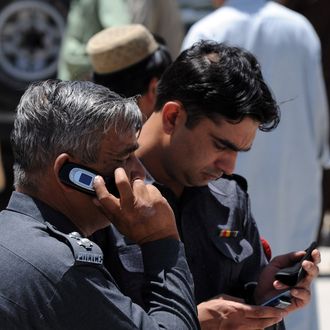 Pakistani policemen use their mobile phones at a street in Quetta on May 20, 2010. AFP PHOTO/BANARAS KHAN (Photo credit should read BANARAS KHAN/AFP/Getty Images)