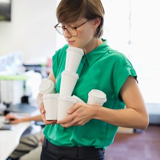 Businesswoman balancing empty coffee cups