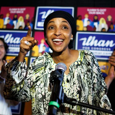 Ilhan Omar smiling at the mic after winning her primary