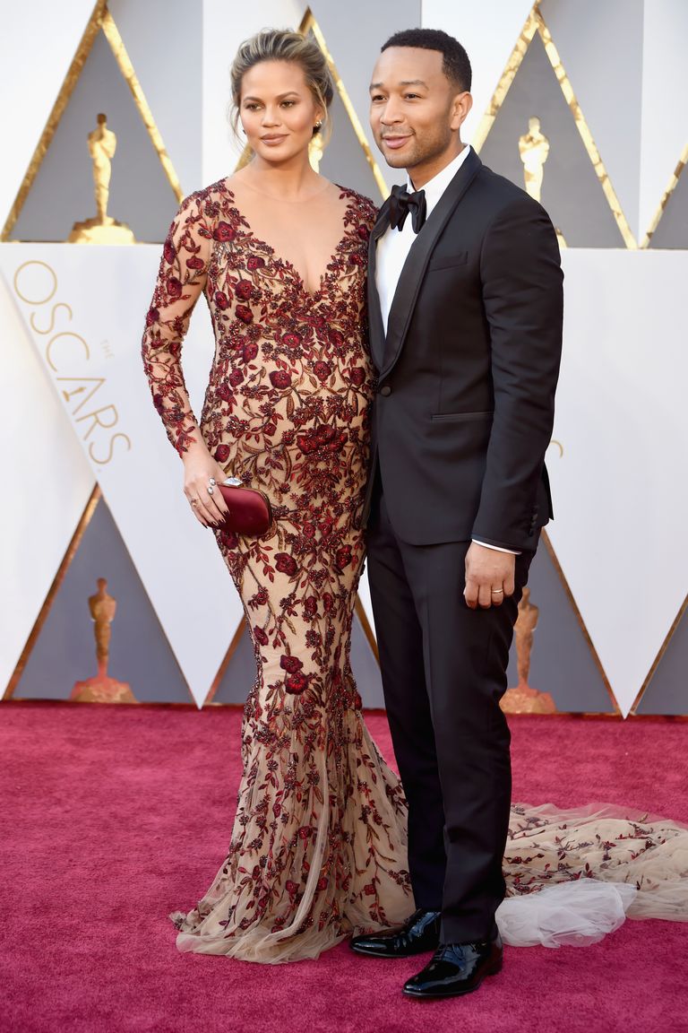 Chrissy Teigen and John Legend 
Dress by Marchesa; jewels by Lorraine Schwartz; clutch by Swarovski; watch by Bulgari (on Legend).