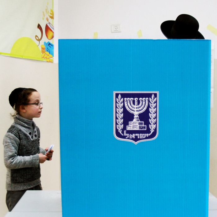 An Israeli ultra-orthodox Jewish man, accompanied by his children, prepares to cast his ballot at a polling station in Bnei Brak, near the city of Tel Aviv, on March 17, 2015. 