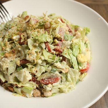 With iceberg lettuce, tomato, garbanzo beans, artichoke hearts, salami, pepperoni, boiled egg, and sweet basil dressing