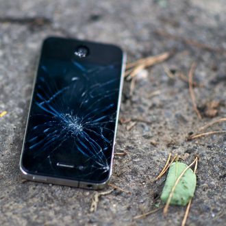 A broken and inoperable mobile phone lays on the ground
