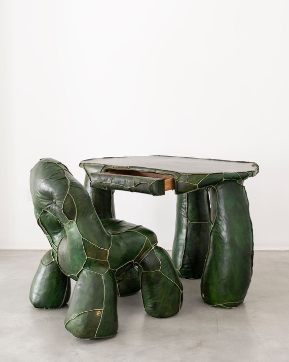 A bumpy green leather chair in front of a patchwork green leather desk.