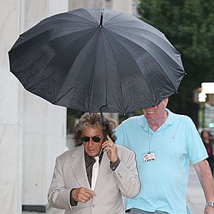"What? I can’t hear you! Oh … yeah, yeah, Frank the Unnecessary Umbrella Holder is with me."