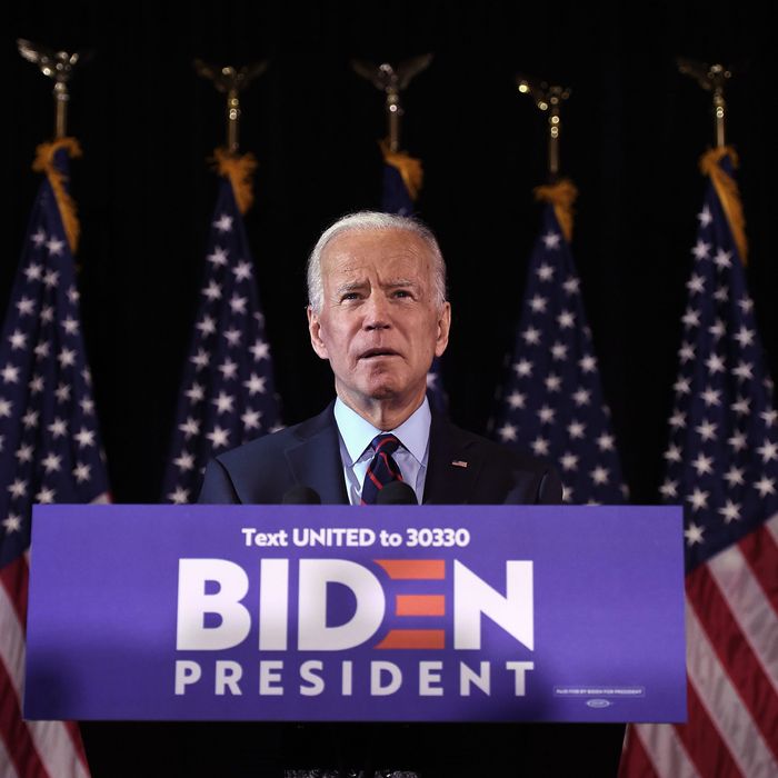 Joe Biden standing at lectern with American flags in the background