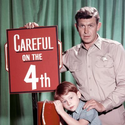 Andy Griffith, US actor, and Ron Howard, US actor, pose beside a large firework, with a sign reading 'Careful on the 4th' in a publicity portrait issued for the US television series, 'The Andy Griffith Show', USA, circa 1963. The sitcom starred
