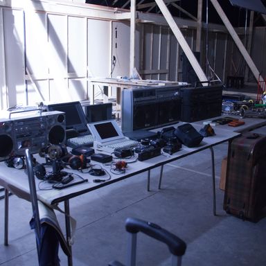 An assortment of boom boxes awaits lucky ’80s extras with (presumably) strong arms. The deeper the bass, the heavier the blaster.