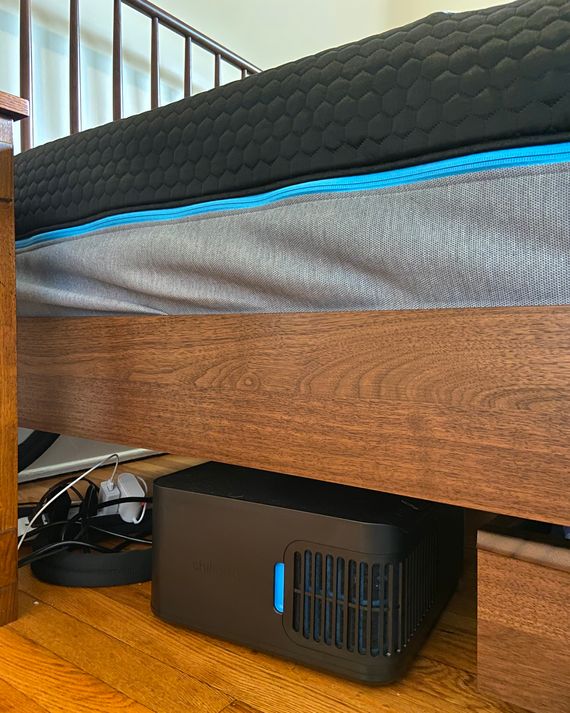 A black control unit underneath a bed.