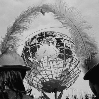 Souvenir hats on the heads of two young visitors to the New York World's Fair frame the fair's symbol, the Unisphere in New York, May 11, 1965. Fair officials are hoping for a record turnout during this second and last year of the fair. (AP Photo/Dave Pickoff)