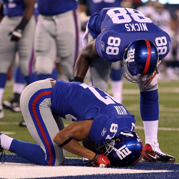 Domenik Hixon #87 of the New York Giants kneels on the turf in pain as teammate Hakeem Nicks #88 stands over him.