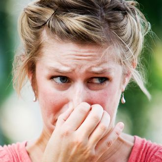 Woman holding nose outdoors