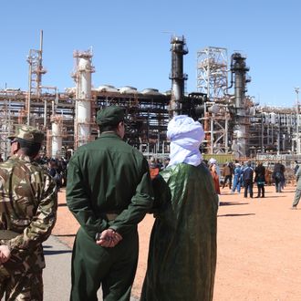 FILE - In this Jan 31, 2013 file photo, Algerian soldiers and officials stand in front of the gas plant in Ain Amenas, seen in background, during a visit organized by the Algerian authorities for news media. In an Oct. 3, 2012 internal al-Qaida letter found by the AP, international terrorist Moktar Belmoktar is excoriated for his unwillingness to follow orders and critiqued for his failure to carry out any large attack. His ego bruised, he quit and formed his own group to compete directly with his former employer. Within months, he carried out two attacks, in Algeria and Niger, so large that they rivaled the biggest operations undertaken by al-Qaida's wing on the continent. In January, his cell penetrated a BP-operated gas plant in Algeria, kidnapping over 600 people, the largest hostage-crisis in recent memory. (AP Photo, File)
