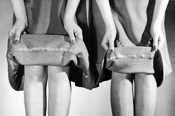 Two models lift the hems of their skirts to demonstrate the difference between a three-inch, pre-war hemline (at left) and the two-inch hemline adopted to save fabric during the course of the war, 1942. (Photo by Nina Leen/Pix Inc./The LIFE Picture Collection/Getty Images)