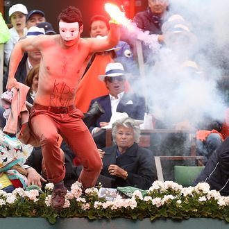 PARIS, FRANCE - JUNE 09: A protester runs onto court with a lit flare before the start of a game in the Men's Singles final match between Rafael Nadal of Spain and David Ferrer of Spain during day fifteen of the French Open at Roland Garros on June 9, 2013 in Paris, France. (Photo by Matthew Stockman/Getty Images)