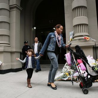 NEW YORK, NY - OCTOBER 26: People walk by flowers and messages that have been left in front of the building where two children were stabbed to death allegedly by their nanny in a family's Upper West Side apartment on October 26, 2012 in New York City. The New York Police department said that the children were discovered in a bathtub by their mother, Marina Krim. Their nanny, Yoselyn Ortega, 50, was lying unconscious nearby with apparent self-inflicted stab wounds. As the investigation continues no charges have been filed at this time. (Photo by Spencer Platt/Getty Images)