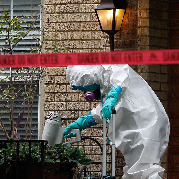 DALLAS, TX - OCTOBER 12: A man dressed in protective hazmat clothing treats the front porch of an apartment where a second person diagnosed with the Ebola virus resides on October 12, 2014 in Dallas, Texas. A female nurse working at Texas Heath Presbyterian Hospital, the same facility that treated Thomas Eric Duncan, has tested positive for the virus. (Photo by Mike Stone/Getty Images)