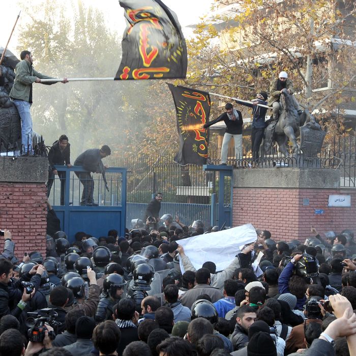 Iranian protesters gather outside the British embassy as some break into it and bring down the British flag (L) in Tehran on November 29, 2011. More than 20 Iranian protesters stormed the British embassy in Tehran, removing the mission's flag and ransacking offices.