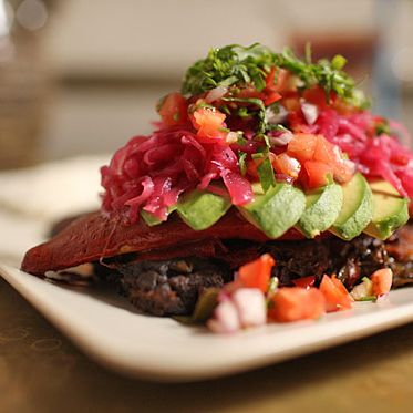 Grilled market fish wrapped in banana leaf with annato seed, fried plantains, roasted peppers, avocado