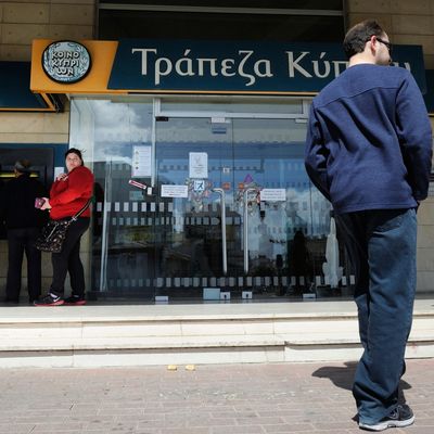 In this image taken Saturday, March 16, 2013, people queue to use an ATM machine outside of Bank of Cyprus branch in southern port city of Limassol, Saturday, March 16, 2013. Many rushed to cooperative banks which are open Saturdays in Cyprus after learning that the terms of a bailout deal that the cash-strapped country hammered out with international lenders includes a one-time levy on bank deposits. The move, decided in an extraordinary meeting of the finance ministers of the 17-nation eurozone in the early hours Saturday, is a major departure from established policies. Analysts have warned that making depositors take a hit threatens to undermine investors' confidence in other weaker eurozone economies and might possibly lead to bank runs.