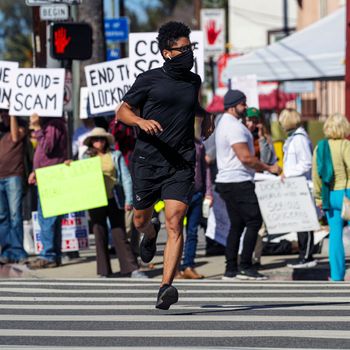 A man jogs by Covid vaccine and mask mandate protestors.