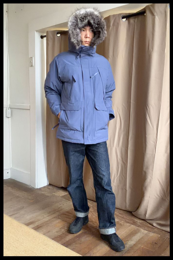 Photo of Strategist senior writer Michael Zhao wearing the Quince Men's Responsible Down Hooded Parka in blue.