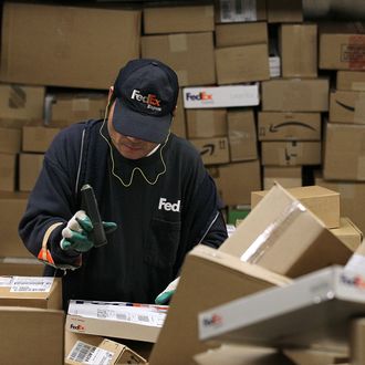 OAKLAND, CA - DECEMBER 13: A FedEx worker scans a pile of boxes at the FedEx sort facility at the Oakland International Airport on December 13, 2010 in Oakland, California. FedEx Corp. is predicting that Monday will be the busiest day in company history for delivering packages worldwide with an expected 16 million shipments, up close to 13% from last year's biggest shipping day. (Photo by Justin Sullivan/Getty Images)