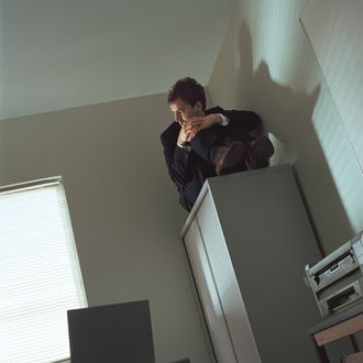 Businessman sitting on filing cabinet, looking out window