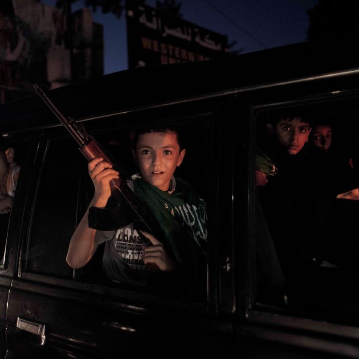 A boy holds with a banner and a rifle drives up a mainstreet in Gaza city as the ceasefire celebrations begins.