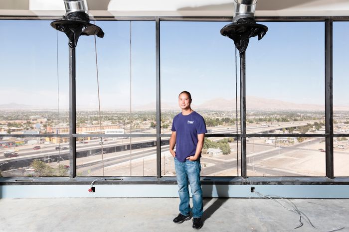 Tony Hsieh stands in front of large windows that look out onto a construction site in Las Vegas. 