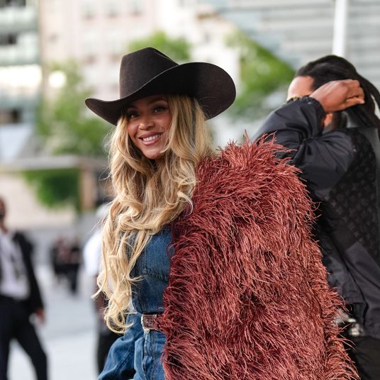 Beyoncé Knowles wears a cowboy hat, a burgundy faux fur fluff coat on one shoulder, and a blue denim shirt during Louis Vuitton Paris Fashion Week - Menswear Spring/Summer 2026 show.