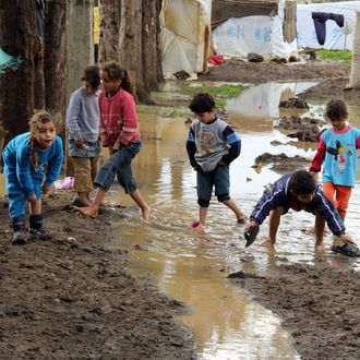 Syrian refugee kids play in the mud after rain as rain and winter worsens the living conditions of Syrian refugees living in a refugee camp in Akkar, Lebanon on January 02i 2014. 