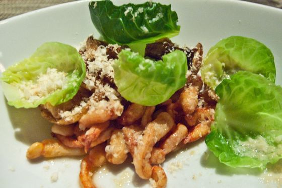 An amuse of lobster legs with Brussels sprout leaves.