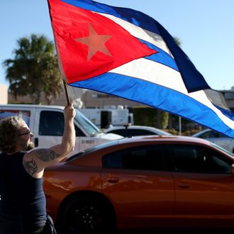 MIAMI, FL - DECEMBER 17: Abdel Rodriguez holds a Cuban flag as he stands outside the Little Havana restaurant Versailles, as people absorb the news that Alan Gross was released from a Cuban prison and that U.S. President Barack Obama wants to change the United States Cuba policy on December 17, 2014 in Miami, United States. Alan Gross, the American contractor had spent five years in Cuban jail. (Photo by Joe Raedle/Getty Images)