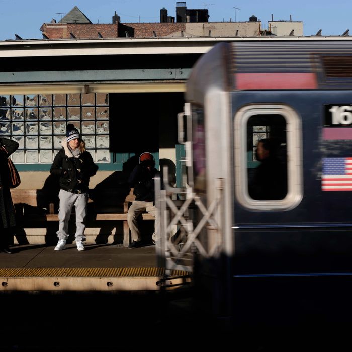 Commuters watch as a train enters the 40th St-Lowry St Station, where a man was killed after being pushed onto the subway tracks, in the Queens section of New York, Friday, Dec. 28, 2012. Police are searching for a woman suspected of pushing the man and released surveillance video Friday of her running away from the station.