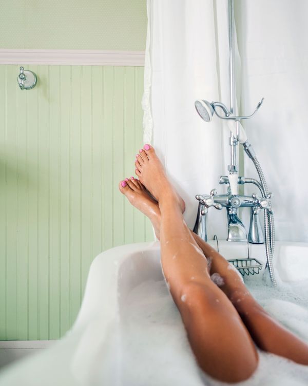 Relaxing in shower. Rear view of beautiful young naked woman