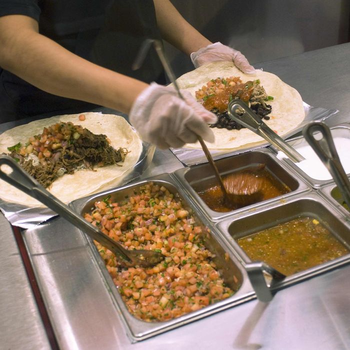 Workers prepare burritos at a Chipotle Mexican Grill in Midtown in New York.