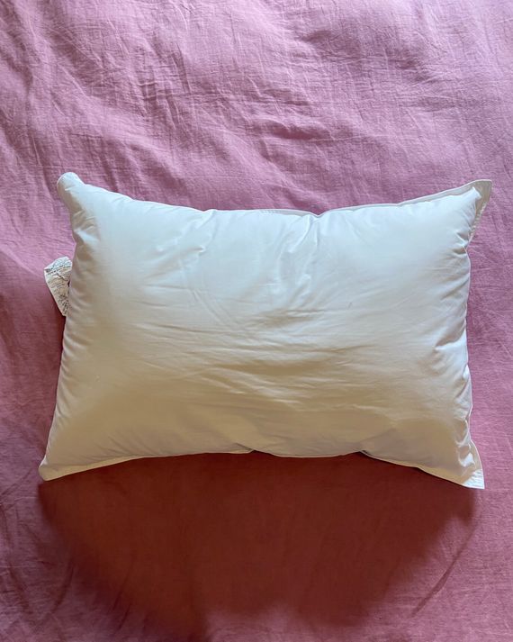 A white pillow on a pink duvet.