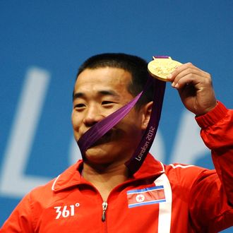 Yun Chol Om of DPR Korea celebrates with the gold medal on the podium after the Men's 56kg Weightlifting on Day 2 of the London 2012 Olympic Games at ExCeL on July 29, 2012 in London, England.