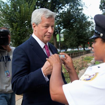JPMorgan Chase Chairman, President and CEO Jamie Dimon presents his driver's license to Justice Department security officer G. Rocher, as he arrives at the Justice Department in Washington, Thursday, Sept. 26, 2013. An $11 billion national settlement is under discussion to resolve claims over JPMorgan's handling of mortgage-backed securities in the run-up to the recession, said a government official familiar with ongoing negotiations among bank, federal and New York state officials.