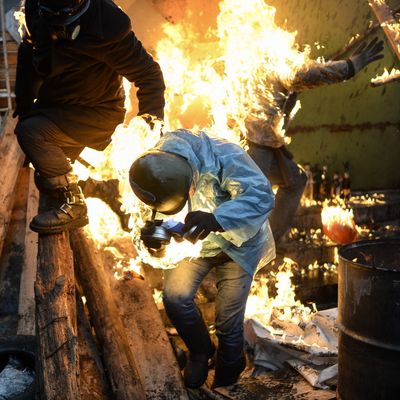 Protesters catch fire as they stand behind burning barricades during clashes with police on February 20, 2014 in Kiev. Ukraine's embattled leader announced a 