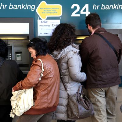People withdraw money from a cash-point machine in the Cypriot capital Nicosia on March 17, 2013. The Cyprus government postponed a planned emergency session of parliament on Sunday to debate a controversial EU bailout, state media said, as the scale of opposition to its terms became clear.